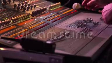 男手在舞台背景下的音乐会上使用音响数字调音台